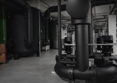 Großdimensionierte, schwarz isolierte Rohrleitungen in einer Industrieanlage.