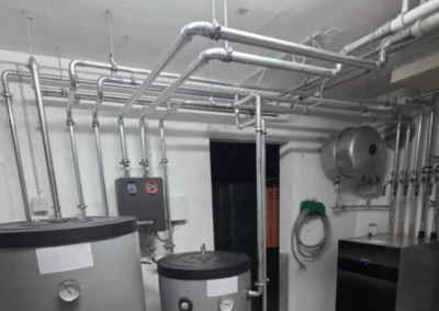 Unisolierte Heizungsleitungen in einem Technikraum vor der Dämmung.